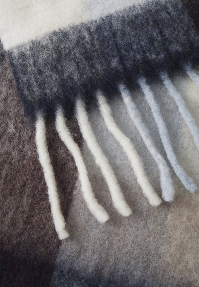 Soft wool blanket in shades of grey, white, and brown. Features fringed edges and a textured finish with a gradient pattern.