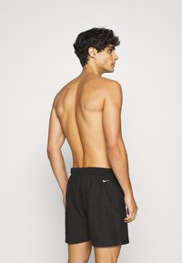 Zwarte sportshorts met een elastische tailleband, voorzien van een wit Nike-logo aan de linkerkant. Soepel, lichtgewicht materiaal.