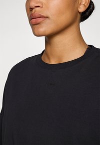 Zwart T-shirt met korte mouwen en een ronde halslijn, voorzien van een subtiel reliëflogo op de borst, gemaakt van zacht katoen.