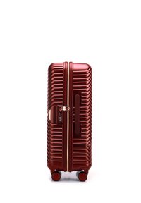 Red hardshell suitcase with a ribbed design, featuring a combination lock, retractable handle, and four wheels for mobility.