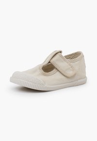 Chaussure beige pour tout-petit en toile avec bride à scratch et bout en caoutchouc texturé, légèrement inclinée pour montrer les détails latéraux et avant.