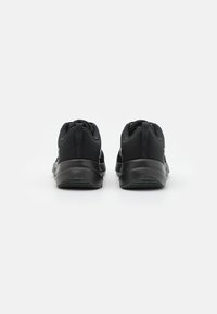 Zapatos deportivos negros con una parte superior de textura suave, cuellos acolchados y suelas de goma. Presentan un diseño elegante con acentos mínimos.