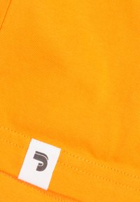 Oranje stof met een gestructureerde weving; bevat een wit label met een zwart gestileerde letter 'P' aan de zoom.