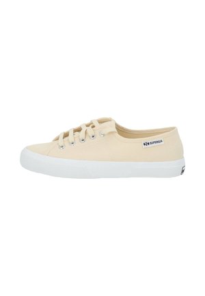 Light beige canvas sneaker with white rubber sole, six eyelet lace-up design, and small black logo label on the side.