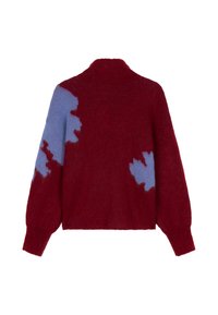 Rode gebreide trui met een hoge kraag, met blauwe abstracte patronen op de mouwen en zijkanten. Zachte textuur, oversized pasvorm en verlaagde schouders.