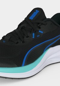 Μαύρο αθλητικό παπούτσι Puma με μπλε λεπτομέρειες, μαύρα κορδόνια και λευκή σόλα με τιρκουάζ λεπτομέρειες. Δεν διακρίνεται κάποιο άτομο.