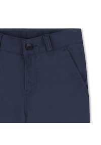 Pantalon en mélange de polyester bleu marine avec une fermeture à bouton unique, des passants de ceinture et des poches avant avec des détails cousus. Texture lisse.