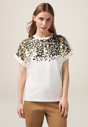 Weißes T-Shirt mit kurzen Ärmeln, das im oberen Bereich mit einem Verlauf aus schwarzen und goldenen runden Pailletten versehen ist. Weicher Baumwollstoff, lässige Passform.