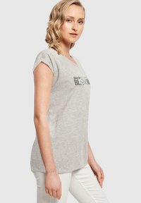 šedé tílko s krátkým rukávem a výstřihem do V, s černým potiskem "čas k rozkvětu", vyrobené z měkké směsi bavlny, s volným střihem.