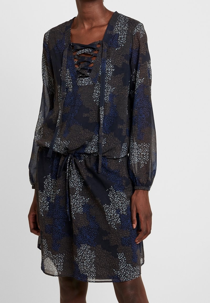 Tmavě květinové šaty s šněrovacím výstřihem, dlouhými rukávy a elastickým pasem. Tkanina má průsvitnou strukturu s různorodými modro-hnědými vzory.