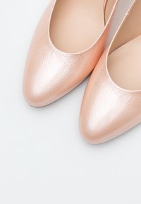 Bailarinas rosas, texturizadas, con una superficie lisa, punta almendrada y un diseño de corte bajo. El interior es beige, enfatizando la simplicidad y la elegancia.
