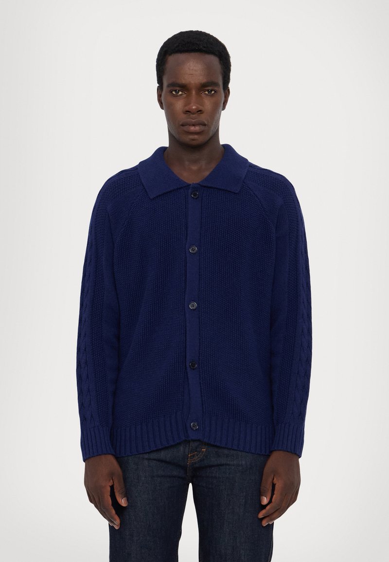 Navy blue knitted cardigan with a collared neck, button closure, and cable-knit accents on the sleeves. Ribbed hem and cuffs.