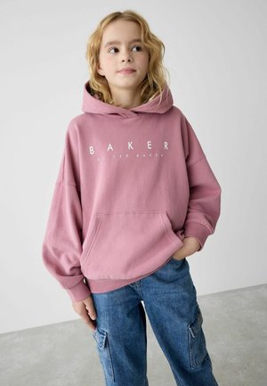 Ružová mikina s kapucňou a predným vreckom s bielym textom "BAKER by TED BAKER." Skombinovaná s modrými denimovými cargo nohavicami s bočnými vreckami.