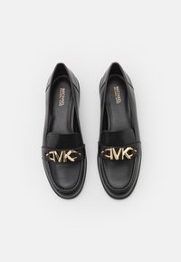 Mocassins en cuir noir avec un bout arrondi et un accent logo MK doré. Texture lisse avec une semelle cousue et une semelle intérieure rembourrée.