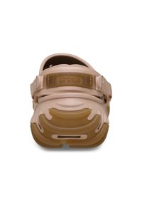 Bleekroze Crocs met een flexibele body, een bandje bij de hiel en een gestructureerd zoolpatroon. Voorzien van een reliëflogo op het bandje.