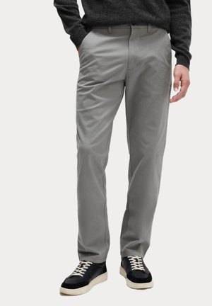 Lys grå chinos med en glat tekstur, lige ben-design, sidelommer og matchende bæltestropper parret med mørke sneakers.