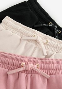 Tre par af joggere præsenteret: sort, lys pink og støvet pink. Hver med elastisk talje og kontrasterende snørebånd med guld accenter.