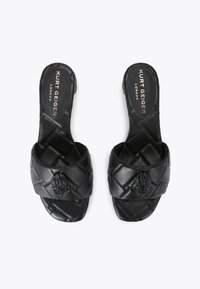 I sandali slide in pelle nera presentano un design intrecciato con un motivo testurizzato e un emblema decorativo sulla cinghia superiore.