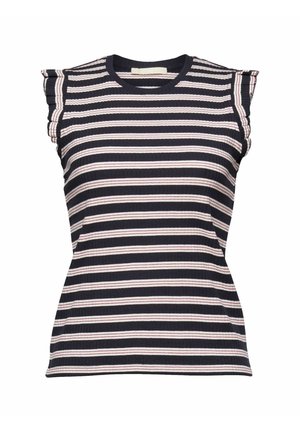 Vrouw draagt een zwart, wit en roze gestreept mouwloos top en witte broek met een hoge taille, voorzien van een knoop en zakken.