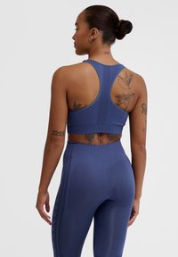 Mörkblå sport-bh med racerback-design, i kombination med matchande högmidjade leggings som har en subtil textur och mönster.