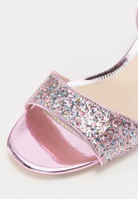 Sandales à talons roses avec une lanière pailletée ornée de sequins multicolores, semelle en cuir verni rose brillant, et design à bout ouvert.