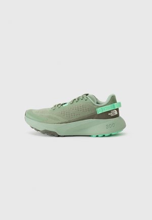 Green athletic shoe with mesh upper, textured overlays, and a thick rubber sole. Features a pull tab and logo detail on the heel.