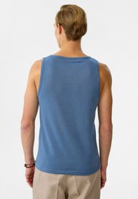Lichtblauwe katoenen tanktop met een ronde hals. Heeft een zachte textuur en een ontspannen pasvorm, zonder zichtbare patronen of accenten.