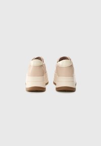 Sneakers con una toma superiore di un rosa chiaro liscio, dettagli crema e una suola bianca spessa. Design arrotondato con una linguetta sul retro per una facile indossabilità.