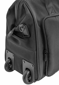 Czarna torba na kółkach z mocnego materiału, z zamykanymi na zamek komorami i plastikowymi kołkami. Posiada wzmocnione narożniki oraz boczny uchwyt dla łatwego transportu.