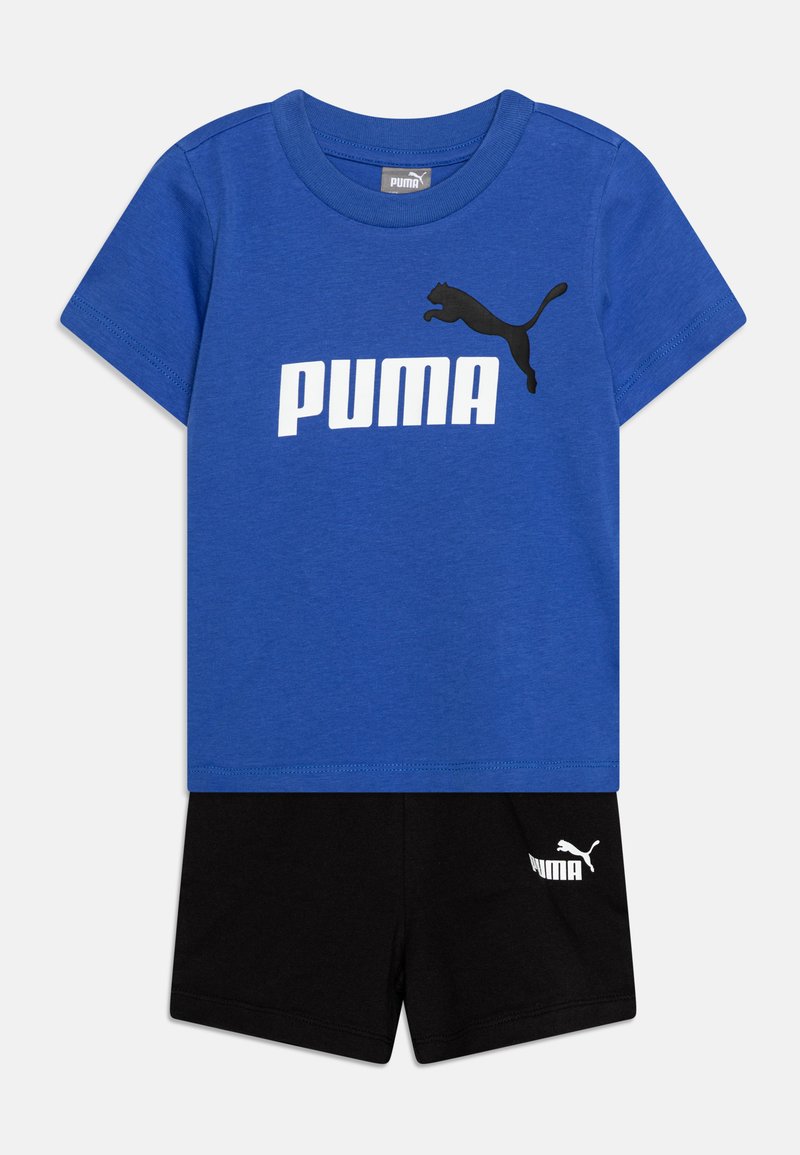Zila kokvilnas t-krekls ar melnu Puma logotipu un atbilstošām melnām kokvilnas šortiem ar baltu Puma tekstu. Īsas piedurknes un brīva piegriezuma.