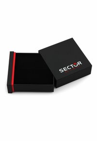 Scatola regalo rettangolare nera con una fascia rossa decorativa, caratterizzata da un logo sul coperchio e un interno morbido nero. Aperta, che rivela l'interno.