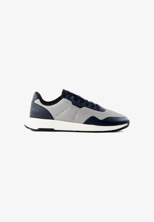 Low-top sneaker met witte mesh bovenkant, navy blauwe overlays, zwarte veters en een gestructureerde witte zool, zijaanzicht naar rechts gericht.