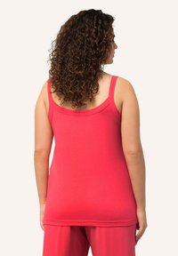Fitted tank top in bright pink cotton, featuring wide shoulder straps and a rounded neckline, with a smooth texture and minimal stitching.
