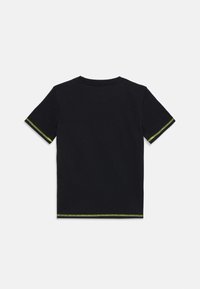T-shirt en coton noir avec des manches courtes, un col rond et des accents verts le long des ourlets des manches. Texture lisse, coupe standard.
