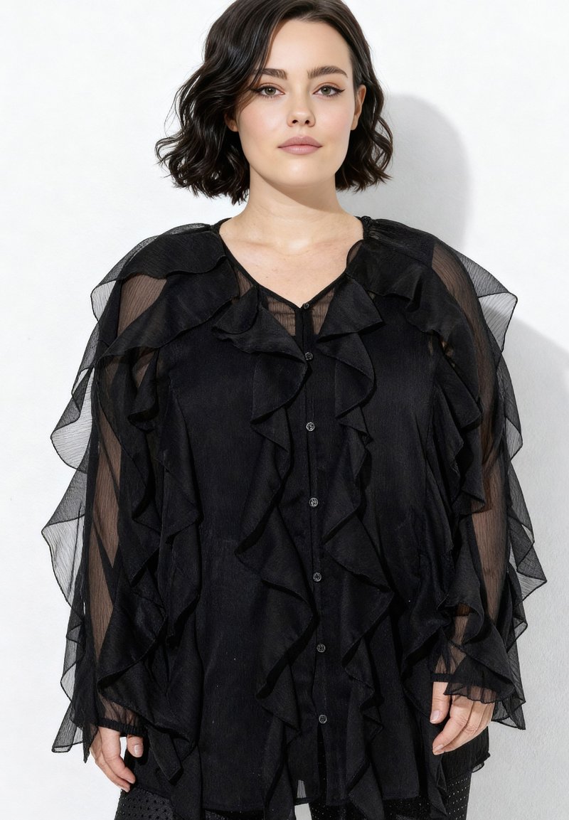 Černá halenka s volánkovými průsvitnými šifonovými rukávy a zapínáním na knoflíky vpředu. Má vrstvený design a průsvitnou strukturu.