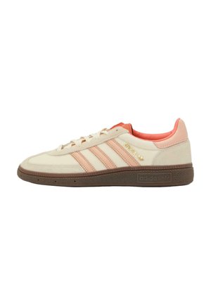 Zapatillas Adidas con parte superior en crema, detalles en rosa, tres rayas rosas y una suela de goma marrón texturizada. Detalles de marca en dorado.