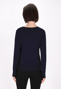 Top a maniche lunghe blu navy con scollatura rotonda, polsini e orlo a coste. Tessuto morbido, vestibilità comoda, con spacco laterale nella parte inferiore.