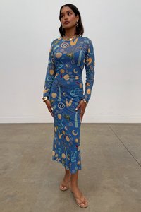 Zilā kleita ar garām piedurknēm, kas piedāvā abstraktus daudzkrāsainus rakstus, pieguļošu siluetu un platām ieplūdām apakšmalā. Gluda, elastīga auduma.