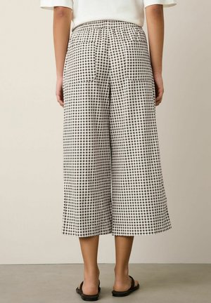 Wide-leg cropped pants with black and white check pattern, elastic waistband, back patch pockets, worn with black sandals.