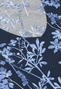 Marineblåt stof med hvide og lyseblå blomsterprint, med en V-formet udskæring og synlige syninger.