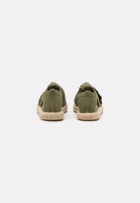 Espadrilles en toile vert olive avec une semelle en jute tressé. Dotées d'un dos arrondi et d'un détail en tissu flexible au niveau du talon pour un enfilage facile.