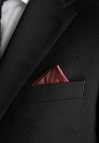 Sacou texturat negru, cu un batista din mătase burgundy având un model complex, introdusă cu grijă în buzunarul de la piept.