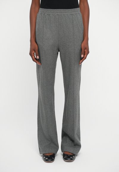 Pantalons larges texturés gris avec une taille élastique. Les plis avant améliorent le design. Accompagnés de chaussures sombres à bout rond.