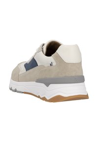 Les baskets présentent un mélange de daim beige et de cuir blanc. Le design inclut un accent gris sur la semelle et des détails bleus sur le côté.