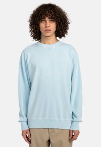 Lyseblå sweatshirt lavet af blødt materiale med rund hals, ribbede manchetter og et lille broderet logo på brystet. Casual pasform.