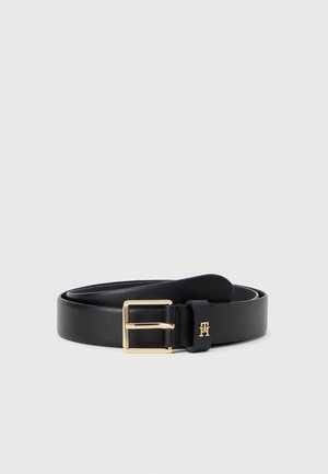 Zwarte leren riem met gouden rechthoekige gesp en klein gouden logo op de riemlus, opgerold op een effen witte achtergrond.
