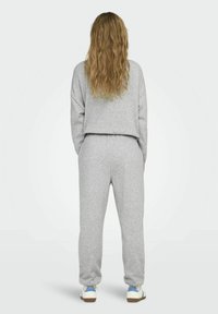 Grijze sweatshirt en joggingbroek set, gemaakt van zachte stof. Heeft een cropped ontwerp, elastische tailleband en casual sneakers met blauwe accenten.