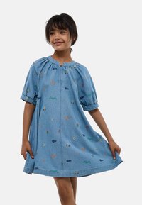 Robe en denim bleu clair avec des manches bouffantes courtes, un col rond et des motifs brodés comprenant des fleurs, des soleils et des formes géométriques.