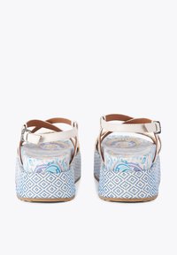 Białe sandały na paski z jasnobrązowym akcentem, z wzorzystą niebiesko-białą podeszwą w kształcie koturny oraz kolorowym, kwiatowym wzorem na wkładce.
