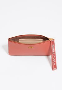 Bolso de cuero coral con herrajes dorados, cierre de cremallera y una correa de tela impresa para la muñeca. Cuenta con un compartimento interior para organización.